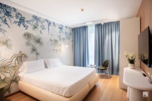 A modern hotel room with a double bed and decorative touches.