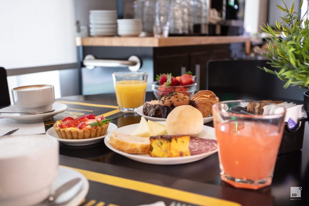 Colazione assortita con bevande e pasticceria su tavolo.
