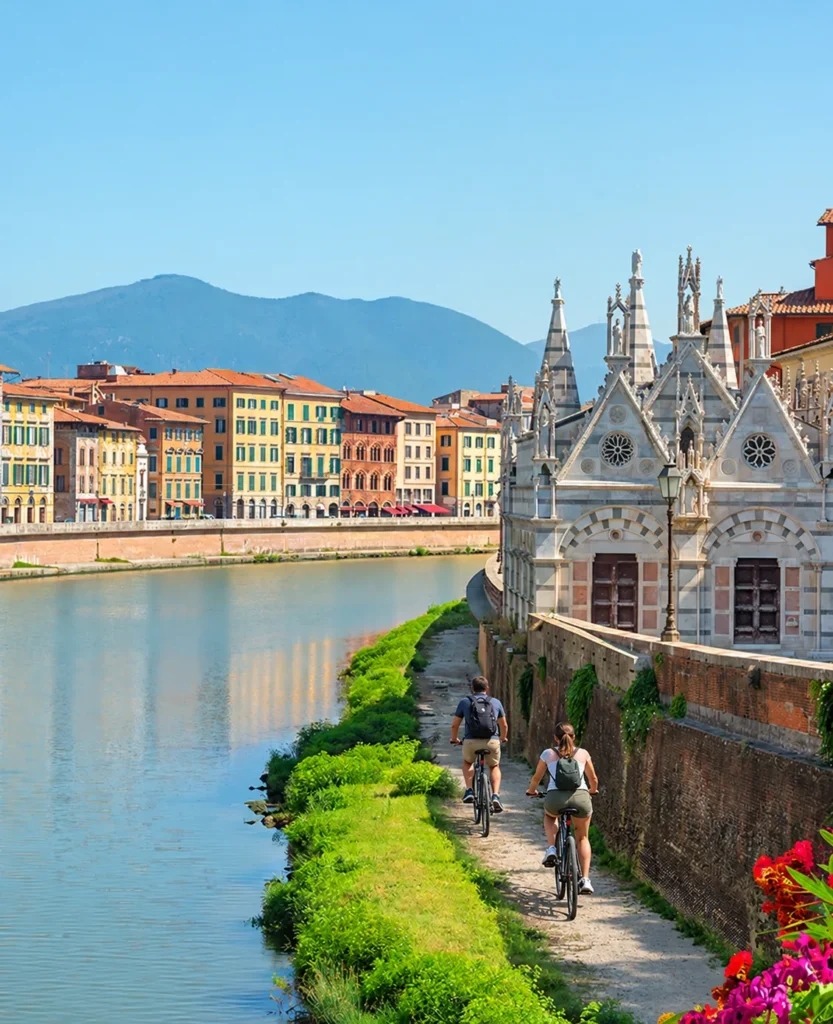 Lungarno di Pisa con la chiesa di Santa Maria della Spina e due ciclisti (immagine modificata con IA)